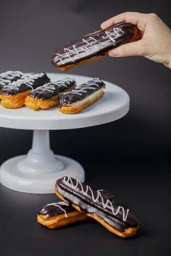 Assorted chocolate eclairs displayed on a white cake stand 库存照片