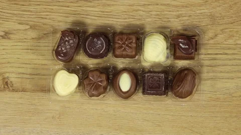 Assorted Chocolate Pralines in Clear Plastic Tray on wood table — Gourmet Gift B Stock Footage 345809330