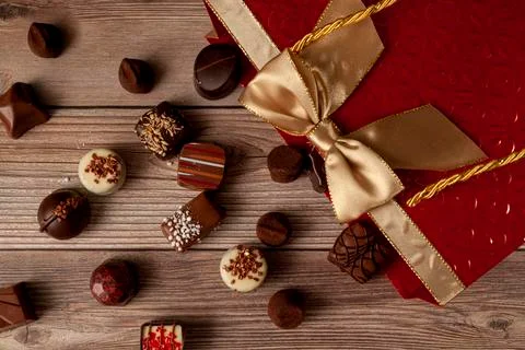 Assorted chocolates in elegant red gift pack with golden ribbon put on top Stock Photos