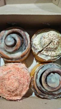 Assorted Cinnamon Rolls with Cream Cheese Frosting and Toppings in Box Foto stock