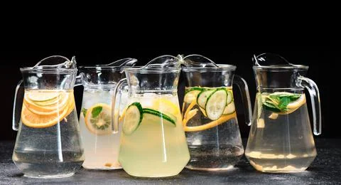 Assorted citrus lemonade with ginger, cucumber, lime, orange in decanters on Stock Photos