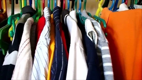 Assorted clothes on a hanger inside a closet Video stock 82550474
