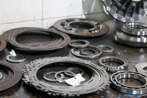 Assorted clutch discs and mechanical parts on a workshop table. 스톡 사진