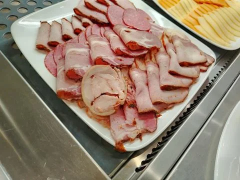 Assorted cold cuts including sliced ham and salami arranged on a white plat.. Foto stock