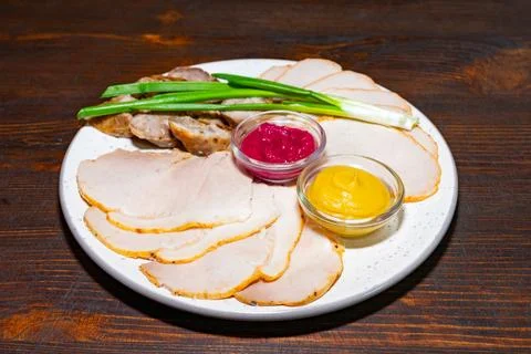 Assorted cold cuts served with dips and green onions on a plate Stock Photos