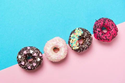 Assorted colored donuts in a row, minimalism on a blue and pink background Stock Photos