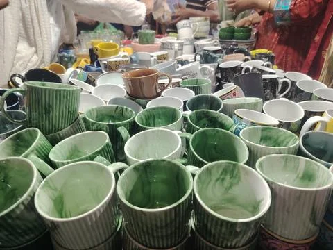 Assorted colorful ceramic mugs displayed together on a table at a market or.. Stock Photos