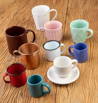 Assorted colorful cups and mugs over wooden table Stock Photos