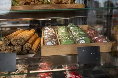 Assorted colorful macarons and sweets in a glass showcase of a modern cafe Stock Photos