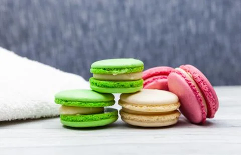 Assorted colorful macaroons on blue background, next to white towel Фото