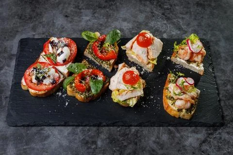 Assorted Crostini and Canap s on Slate Board Featuring Tomato, Cheese, Basil Stock Photos