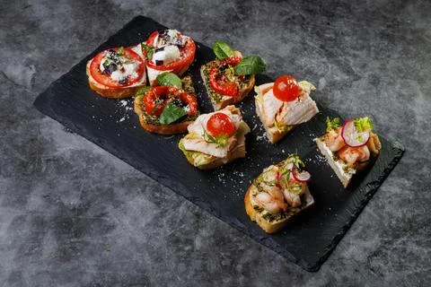 Assorted Crostini and Canap s on Slate Board Featuring Tomato, Cheese, Basil Stock Photos