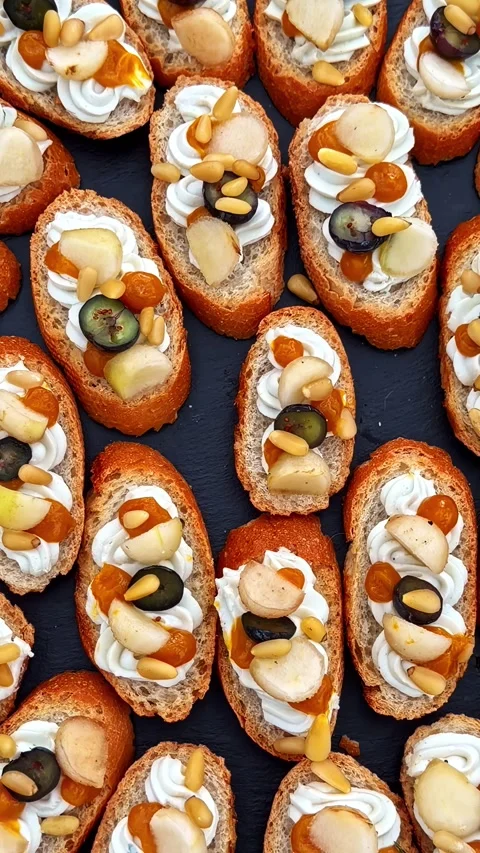 Assorted Crostini with Cheese, Fruit, and Nuts Arranged on Dark Background Stock Footage 337386061