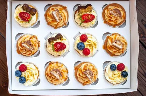 Assorted cupcakes in gift box with fresh strawberries, peanut butter, slated  Stock Photos