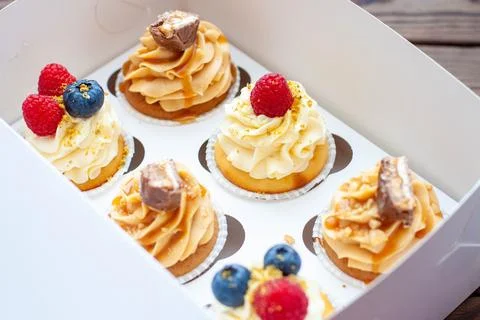 Assorted cupcakes in gift box with fresh strawberries, peanut butter, slated  Stock Photos
