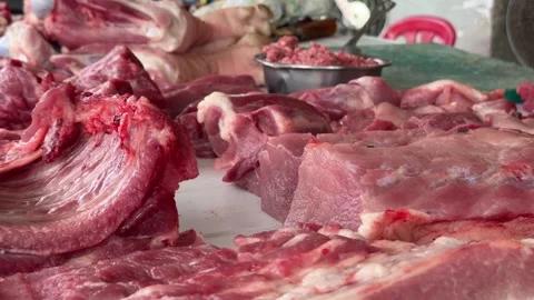 Assorted cuts of fresh raw meat are arranged for sale on a market counter, with Stock Footage 329680396