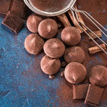 Assorted dark chocolate truffles with cocoa powder on dark blue table Stock Photos