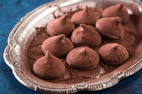 Assorted dark chocolate truffles with cocoa powder on dark blue table Stock Photos