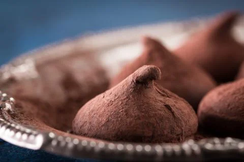 Assorted dark chocolate truffles with cocoa powder on dark blue table Stock Photos