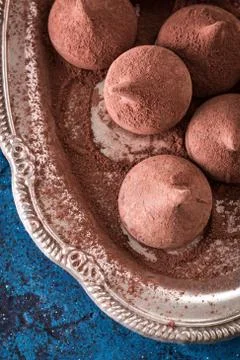 Assorted dark chocolate truffles with cocoa powder on dark blue table Stock Photos
