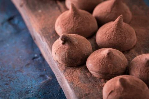 Assorted dark chocolate truffles with cocoa powder on dark blue table Stock Photos