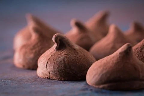 Assorted dark chocolate truffles with cocoa powder on dark blue table Stock Photos