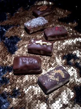 Assorted dark handmade chocolate on the sequins Stock Photos