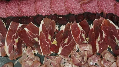 Assorted deli meats, ham, salami, bacon on a black background. Food background Stock Footage 103287742