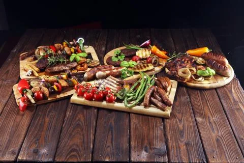 Assorted delicious grilled meat with vegetable on rustic table Stock Photos