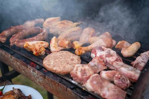 Assorted delicious grilled meat with vegetables over the coals on a barbecue Stock Photos