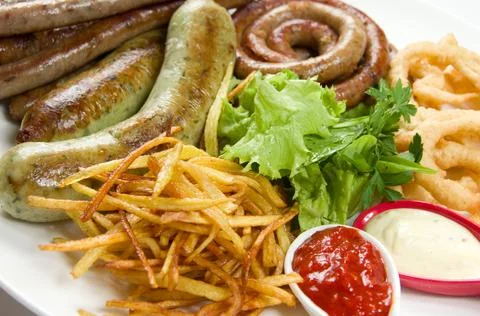 Assorted different fried sausages with fried onion rings, french fries, fresh Fotos de archivo