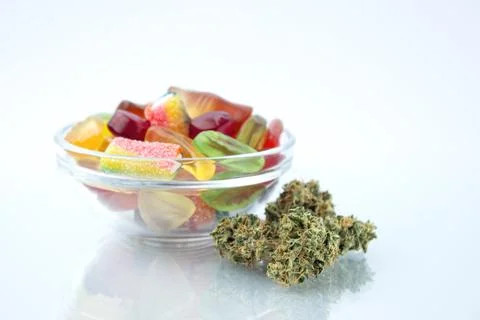 Assorted different gummy candies in a small glass bowl, near in the foregroun Stock Photos