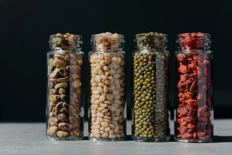 Assorted different ingredients in glass bottles. Pistachio, pine nuts, mung b Foto stock