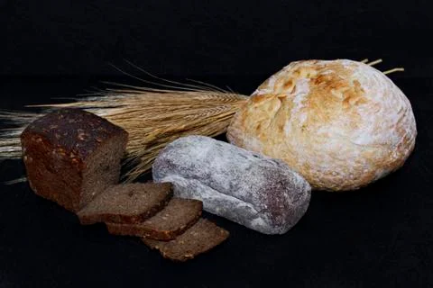 Assorted different kinds of white and black bread on a black background. Stock Photos