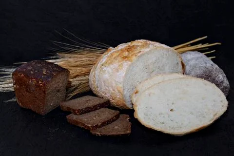Assorted different kinds of white and black bread on a black background. Stock Photos
