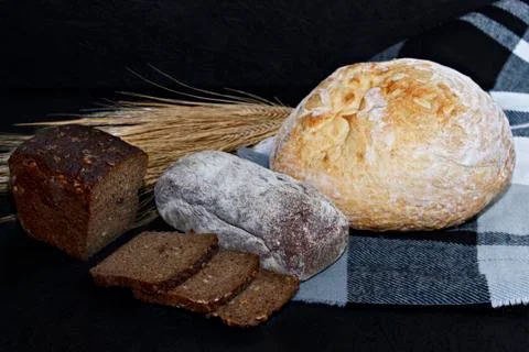 Assorted different kinds of white and black bread on a black background. Stock Photos