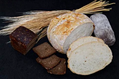 Assorted different kinds of white and black bread on a black background. Stock Photos