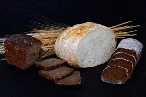 Assorted different kinds of white and black bread on a black background. Stock Photos