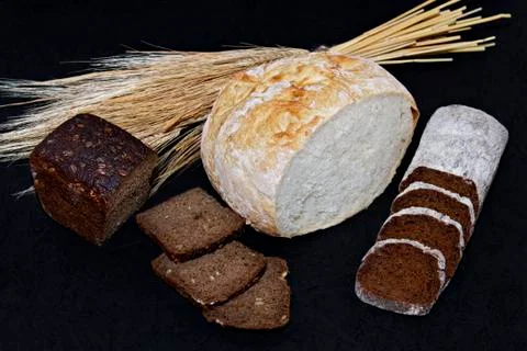 Assorted different kinds of white and black bread on a black background. Stock Photos