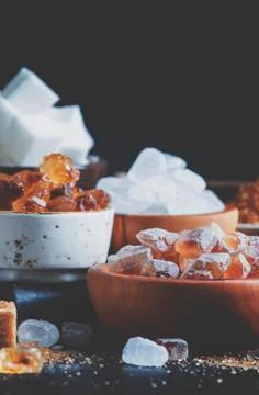 Assorted different types of sugar in bowls on a table on a dark background, s Stock Photos