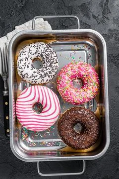 Assorted donuts with chocolate, pink glazed and sprinkles Doughnut. Black Stock Photos