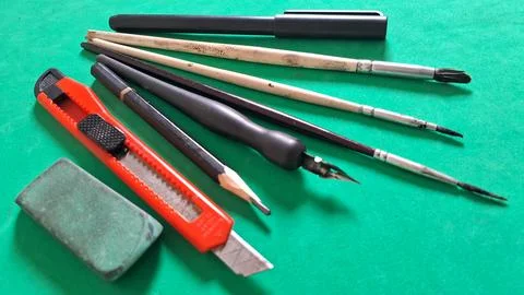 Assorted drawing and writing tools arranged on a vibrant green surface Stock Photos