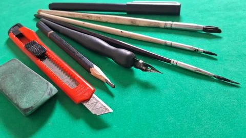 Assorted drawing and writing tools arranged on a vibrant green surface 스톡 사진
