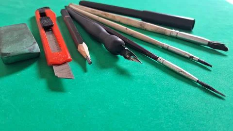 Assorted drawing tools and stationery supplies arranged on green surface 스톡 사진