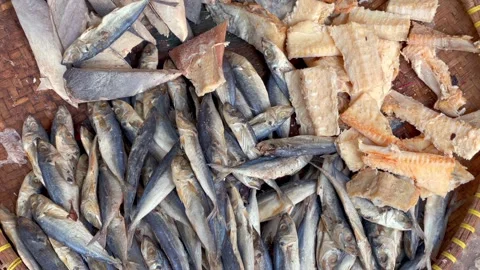 Assorted dried fish on a woven tray at a traditional market Vidéo 337572503