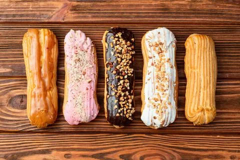 Assorted eclairs on a pastel top view Traditional French dessert Stock Photos