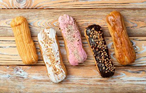 Assorted eclairs on a pastel top view Traditional French dessert Stock Photos