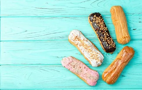 Assorted eclairs on a pastel top view Traditional French dessert Stock Photos