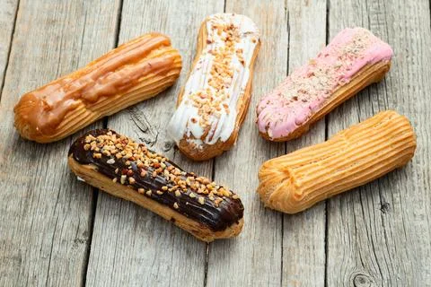 Assorted eclairs on a pastel top view Traditional French dessert Stock Photos