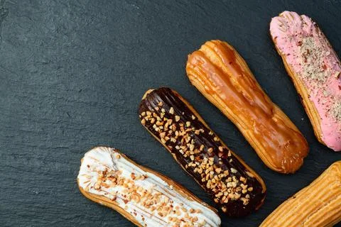 Assorted eclairs on a pastel top view Traditional French dessert Stock Photos